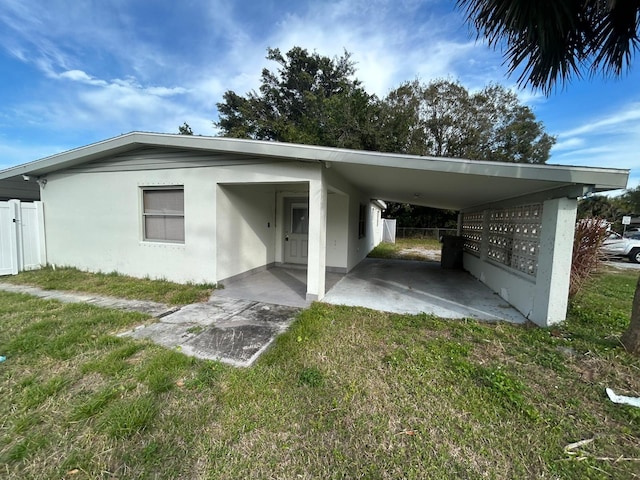 view of parking / parking lot featuring a lawn and a carport