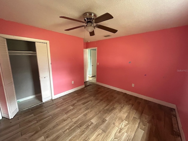 unfurnished bedroom featuring ceiling fan, a closet, a textured ceiling, and hardwood / wood-style flooring