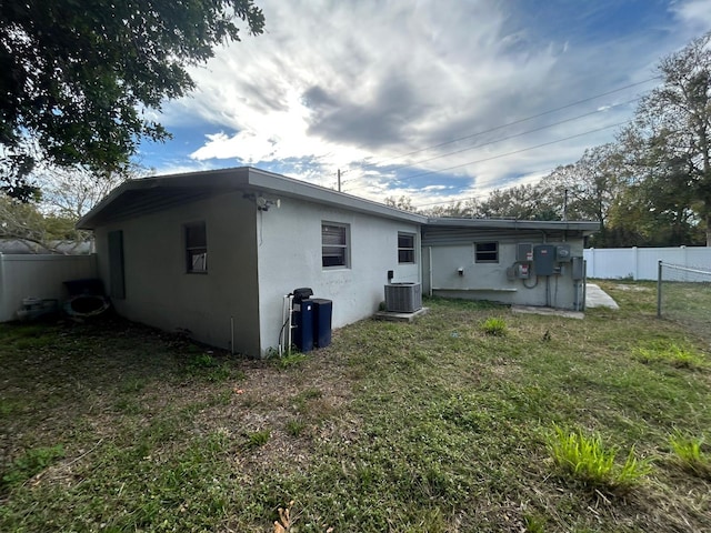 rear view of property with cooling unit and a yard