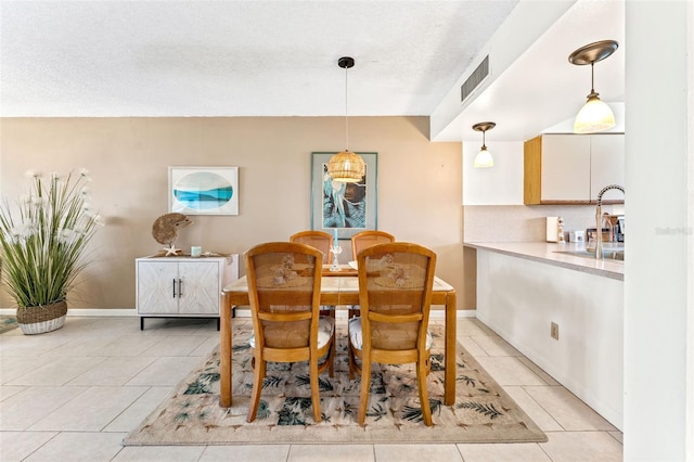 tiled dining room featuring sink and a textured ceiling