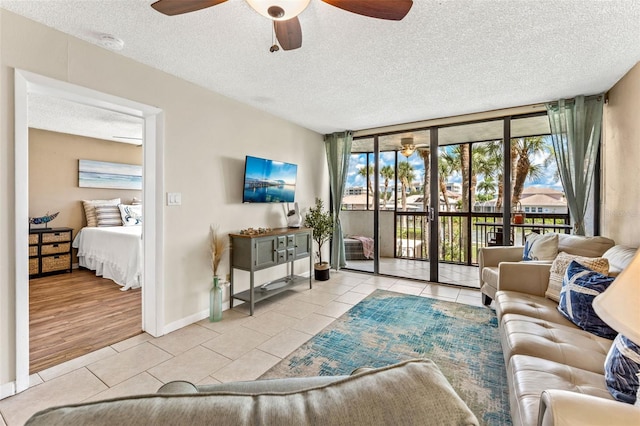 tiled living room with ceiling fan, a wall of windows, and a textured ceiling