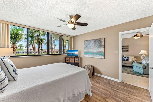 bedroom with multiple windows, a textured ceiling, wood-type flooring, and ceiling fan