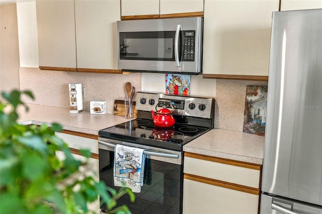 kitchen featuring stainless steel appliances, tasteful backsplash, and white cabinets