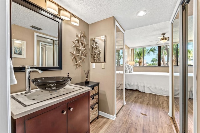 bathroom with vanity, hardwood / wood-style floors, a textured ceiling, and ceiling fan