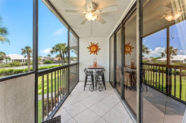 sunroom featuring a water view and ceiling fan