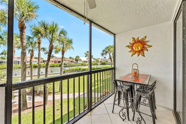 sunroom / solarium featuring a water view and ceiling fan