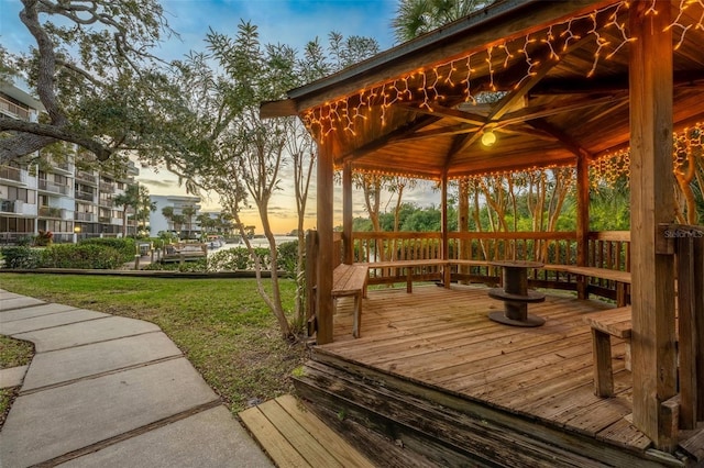 deck at dusk featuring a gazebo and a yard