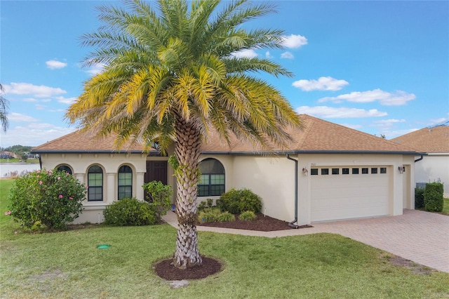 mediterranean / spanish house featuring a garage and a front yard