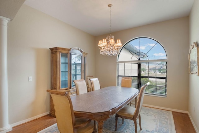 dining room with plenty of natural light, light hardwood / wood-style flooring, ornate columns, and an inviting chandelier