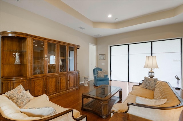 living room featuring dark hardwood / wood-style flooring and a tray ceiling