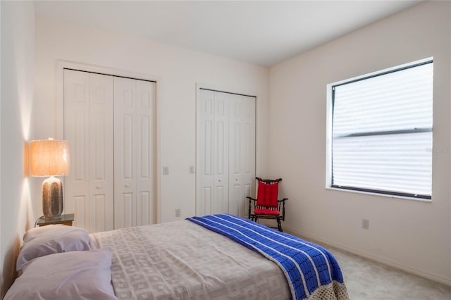 bedroom with multiple closets and carpet flooring