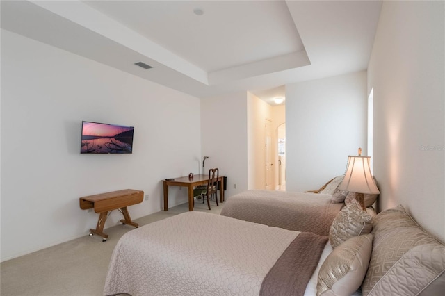 bedroom featuring light colored carpet, connected bathroom, and a tray ceiling