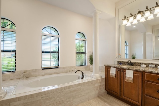 bathroom featuring a relaxing tiled tub, vanity, and ornate columns