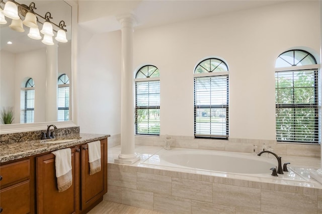 bathroom with tiled bath, vanity, and ornate columns