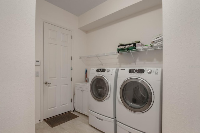 laundry room featuring light tile patterned flooring, separate washer and dryer, and cabinets