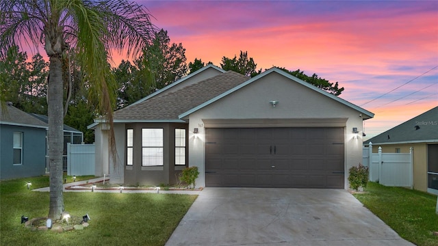 ranch-style home featuring a garage and a lawn