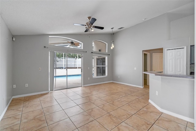 unfurnished living room featuring ceiling fan, light tile patterned floors, and vaulted ceiling