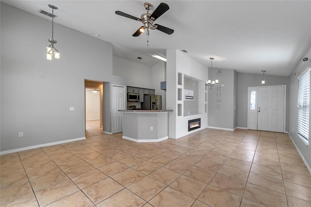 unfurnished living room featuring vaulted ceiling, built in features, light tile patterned flooring, and ceiling fan with notable chandelier