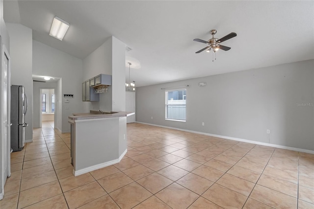 kitchen with ceiling fan with notable chandelier, light tile patterned floors, lofted ceiling, and stainless steel refrigerator