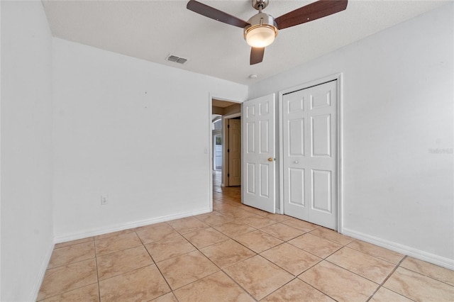 unfurnished bedroom featuring ceiling fan, light tile patterned floors, and a closet