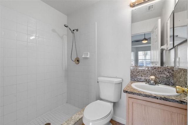 bathroom with tasteful backsplash, vanity, ceiling fan, toilet, and tiled shower