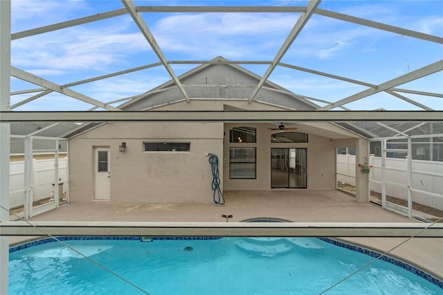 rear view of house with ceiling fan, glass enclosure, and a patio