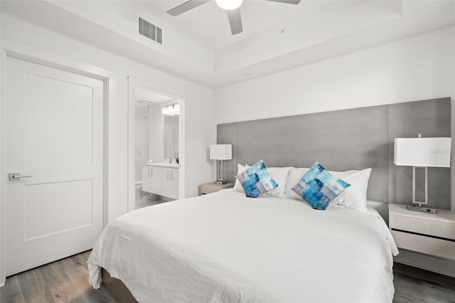 bedroom featuring ceiling fan, a raised ceiling, connected bathroom, and wood-type flooring