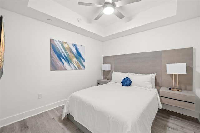 bedroom featuring a raised ceiling, ceiling fan, and hardwood / wood-style floors