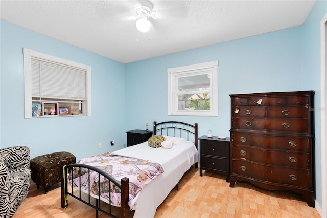 bedroom with ceiling fan, light wood-type flooring, and a textured ceiling