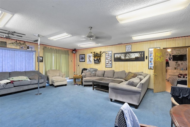 living room with a textured ceiling, ceiling fan, carpet flooring, and wooden walls