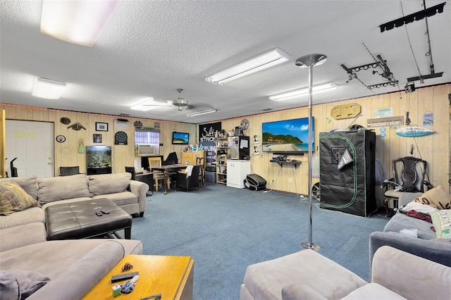 living room featuring wooden walls, ceiling fan, cooling unit, carpet floors, and a textured ceiling