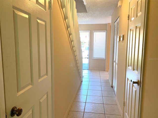 corridor featuring light tile patterned floors and a textured ceiling