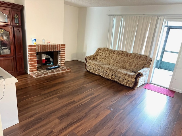 living room featuring a textured ceiling, a brick fireplace, and dark hardwood / wood-style flooring