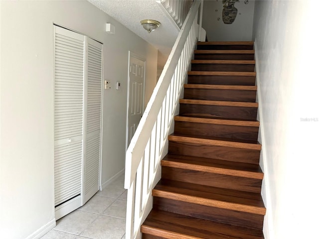 staircase with a textured ceiling and tile patterned floors