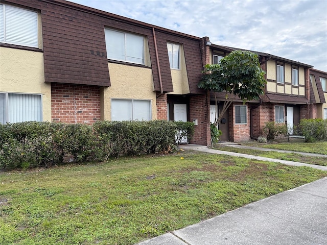 5123 Picadilly Circus Ct Unit 2, Orlando, FL 32839 - view of front of house featuring mansard roof, a front yard, stucco siding, and brick siding