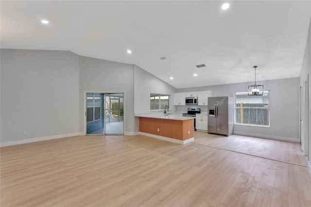 kitchen featuring appliances with stainless steel finishes, open floor plan, a peninsula, white cabinetry, and pendant lighting