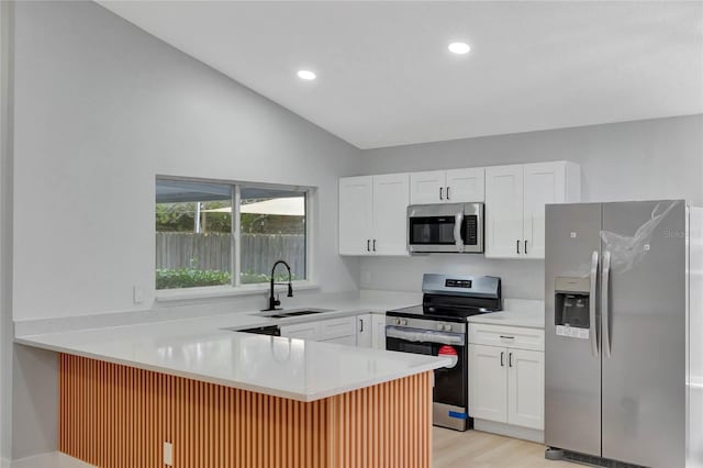 kitchen featuring a peninsula, a sink, white cabinetry, light countertops, and appliances with stainless steel finishes