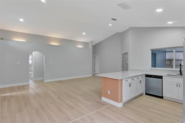 kitchen with arched walkways, open floor plan, a peninsula, white cabinetry, and stainless steel dishwasher