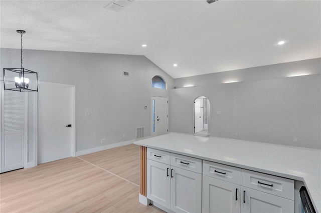 kitchen featuring light wood finished floors, visible vents, hanging light fixtures, vaulted ceiling, and white cabinetry