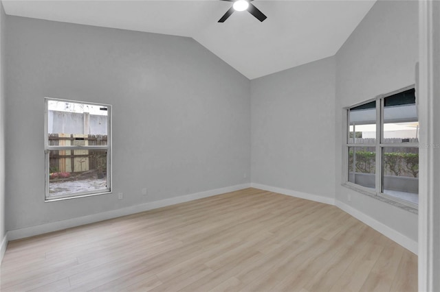 spare room with lofted ceiling, baseboards, a ceiling fan, and light wood-style floors