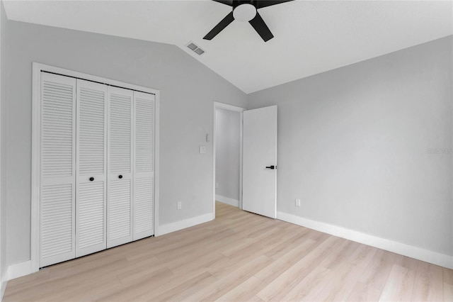 unfurnished bedroom featuring visible vents, baseboards, vaulted ceiling, a closet, and light wood finished floors