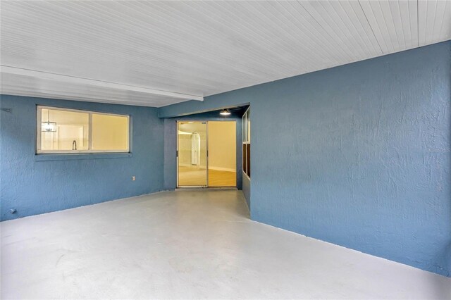 unfurnished room featuring concrete flooring and a textured wall