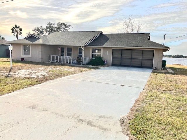 ranch-style house featuring a yard, a garage, a water view, and a porch