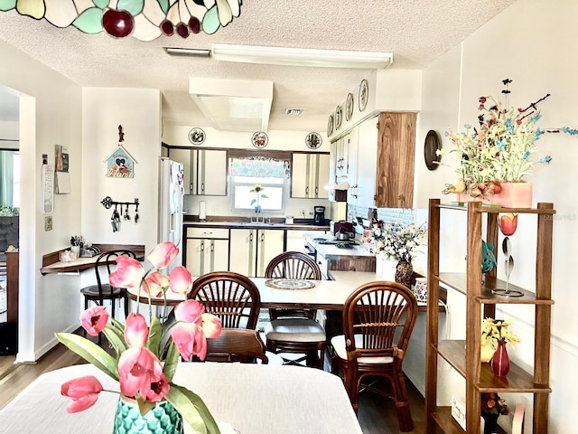 dining area with wood-type flooring and a textured ceiling