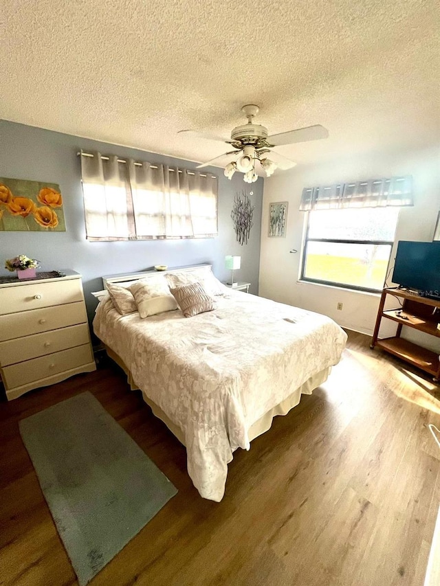 bedroom with multiple windows, a textured ceiling, and ceiling fan