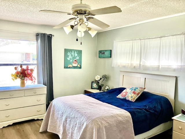 bedroom with a textured ceiling, light hardwood / wood-style flooring, and ceiling fan