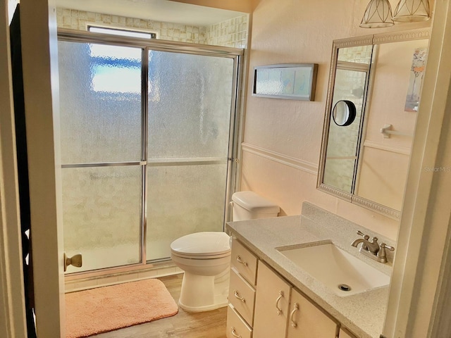 bathroom featuring toilet, vanity, a shower with door, and hardwood / wood-style floors