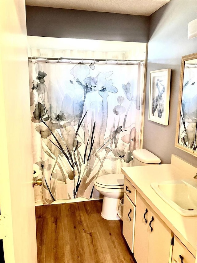 bathroom with vanity, hardwood / wood-style flooring, curtained shower, and toilet