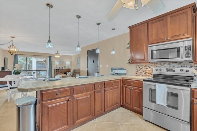 kitchen with decorative backsplash, kitchen peninsula, hanging light fixtures, stainless steel appliances, and light tile patterned floors