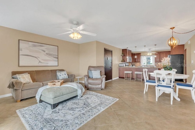 tiled living room featuring ceiling fan with notable chandelier